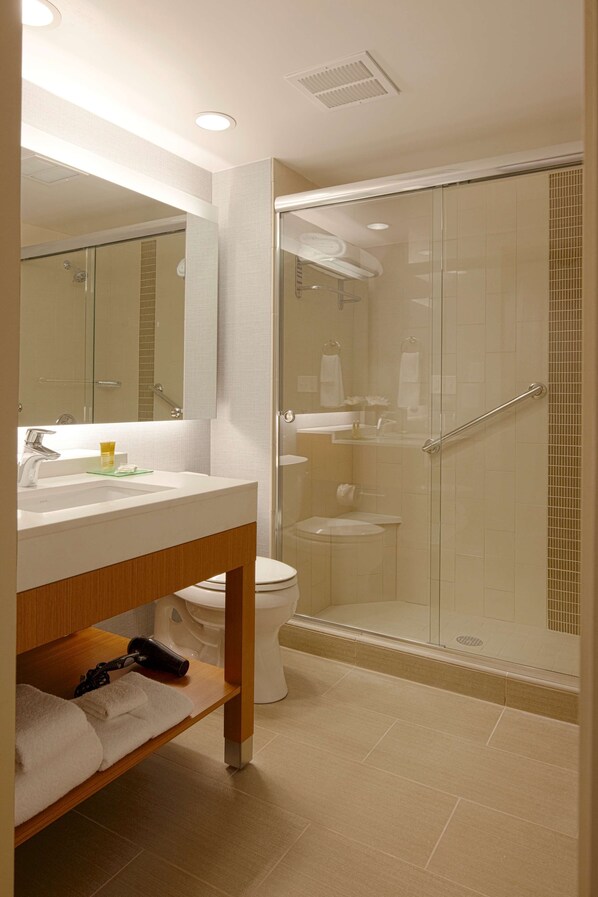 A modern bathroom with a glass-enclosed shower, a white sink, and a mirror above it.