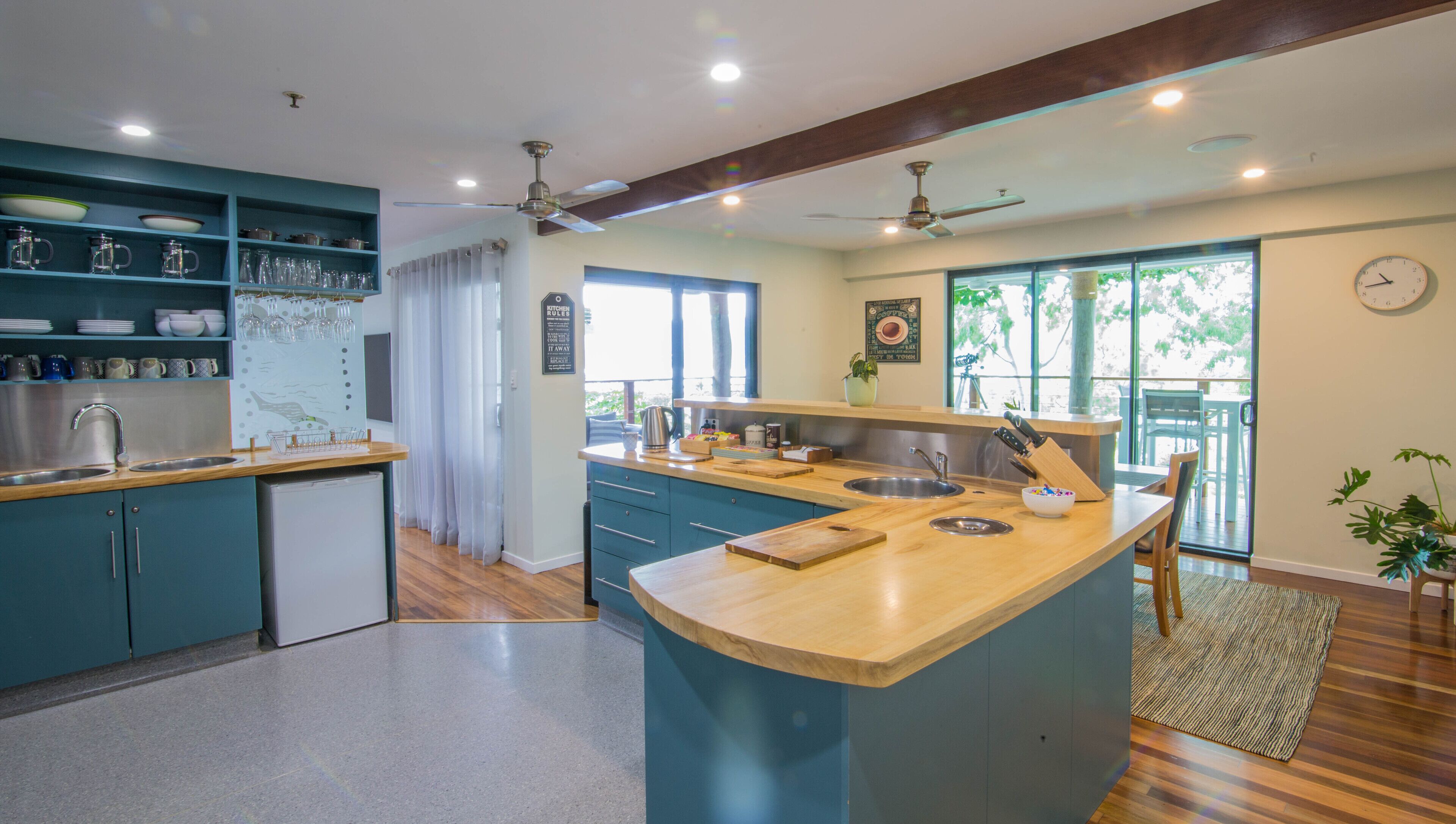 Una cocina moderna con armarios azules, encimera de madera y un amplio ventanal.