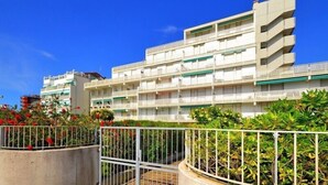 Een meerlaags hotel met balkons, een hekpoort en omliggend groen.