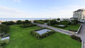 Een aangelegde tuin met paden, een waterpartij en uitzicht op zee.