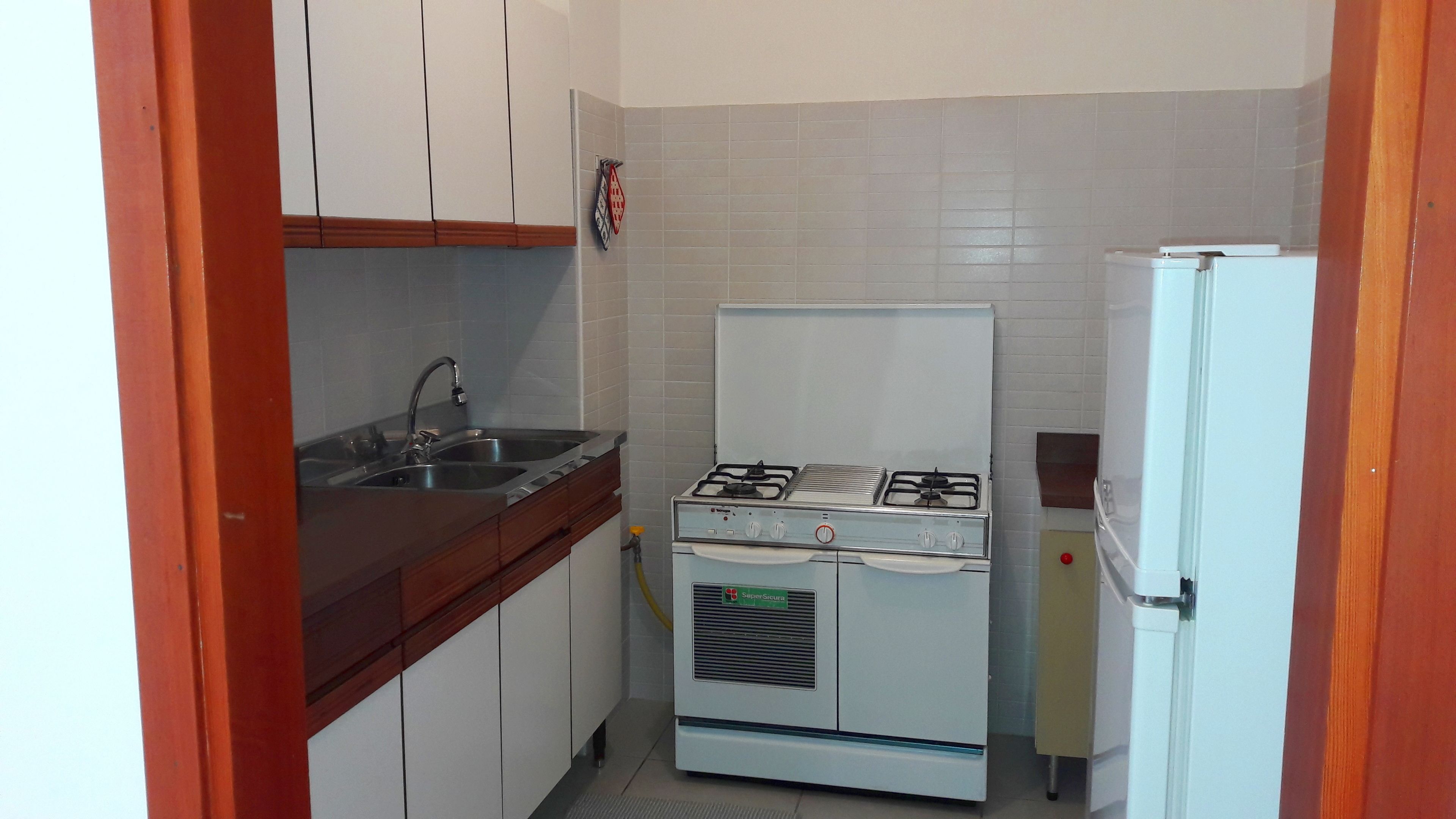 A compact kitchen with a gas stove, a sink, and a refrigerator.