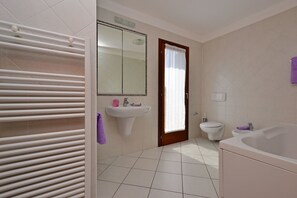 Een aparte badkuip en douche, een diep bad, een regendouche
