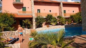 Ein Resort mit Pool, Steinmauern und einem pinkfarbenen Gebäude mit Balkonen.