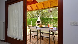 Eine Terrasse mit Tisch, Stühlen, einem Grill und Blick auf einen Garten.