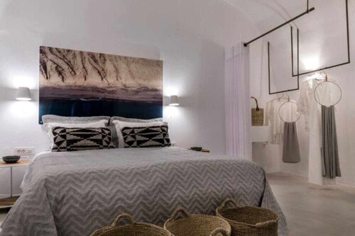 A modern bedroom with a large bed, a wall-mounted artwork, and a minimalist decor style.