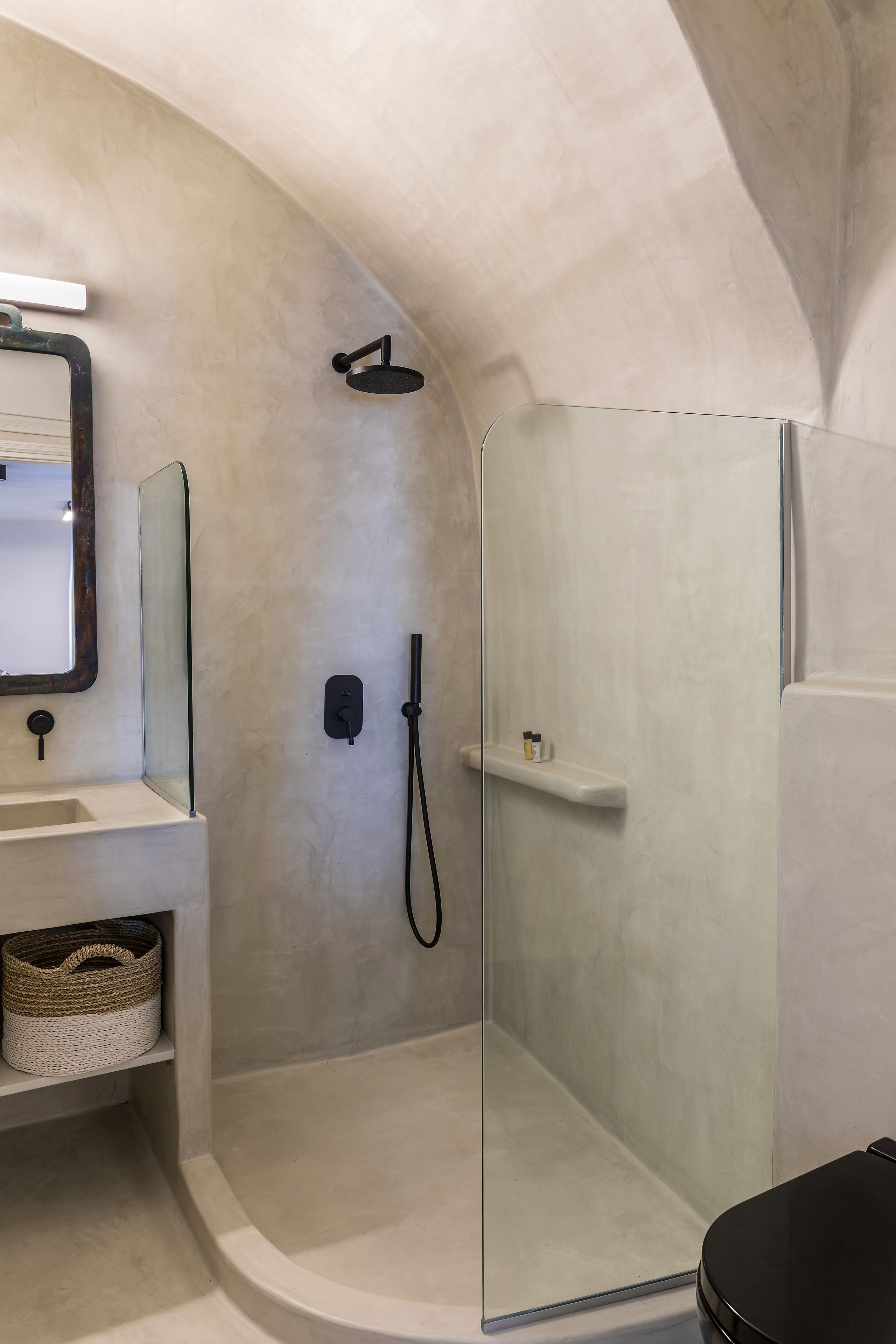Un baño moderno con cabina de ducha de vidrio, un lavamanos blanco y un espejo.