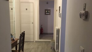 A hallway with a dining area, a ceiling fan, a fire extinguisher, and a radiator. - Nonna Lina Rooms (Florence)