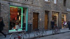 A stone building with a storefront displaying clothing and accessories. - Nonna Lina Rooms (Florence)