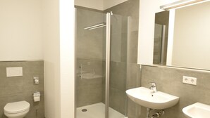 A modern bathroom with a glass-enclosed shower, a white toilet, and a sink with a mirror above it. - Hostel & Pension  Alte Brauerei (Eisenach)