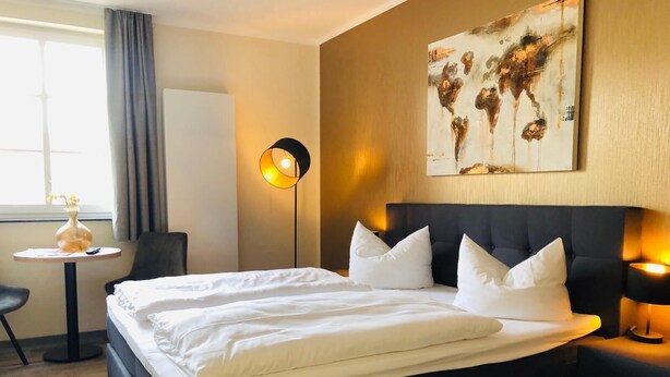 A hotel room with a large bed, bedside tables, a desk, and a painting on the wall. - Hostel & Pension  Alte Brauerei (Eisenach)