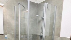 A modern bathroom with a glass-enclosed shower, a white toilet, and a wooden floor. - Hostel & Pension  Alte Brauerei (Eisenach)