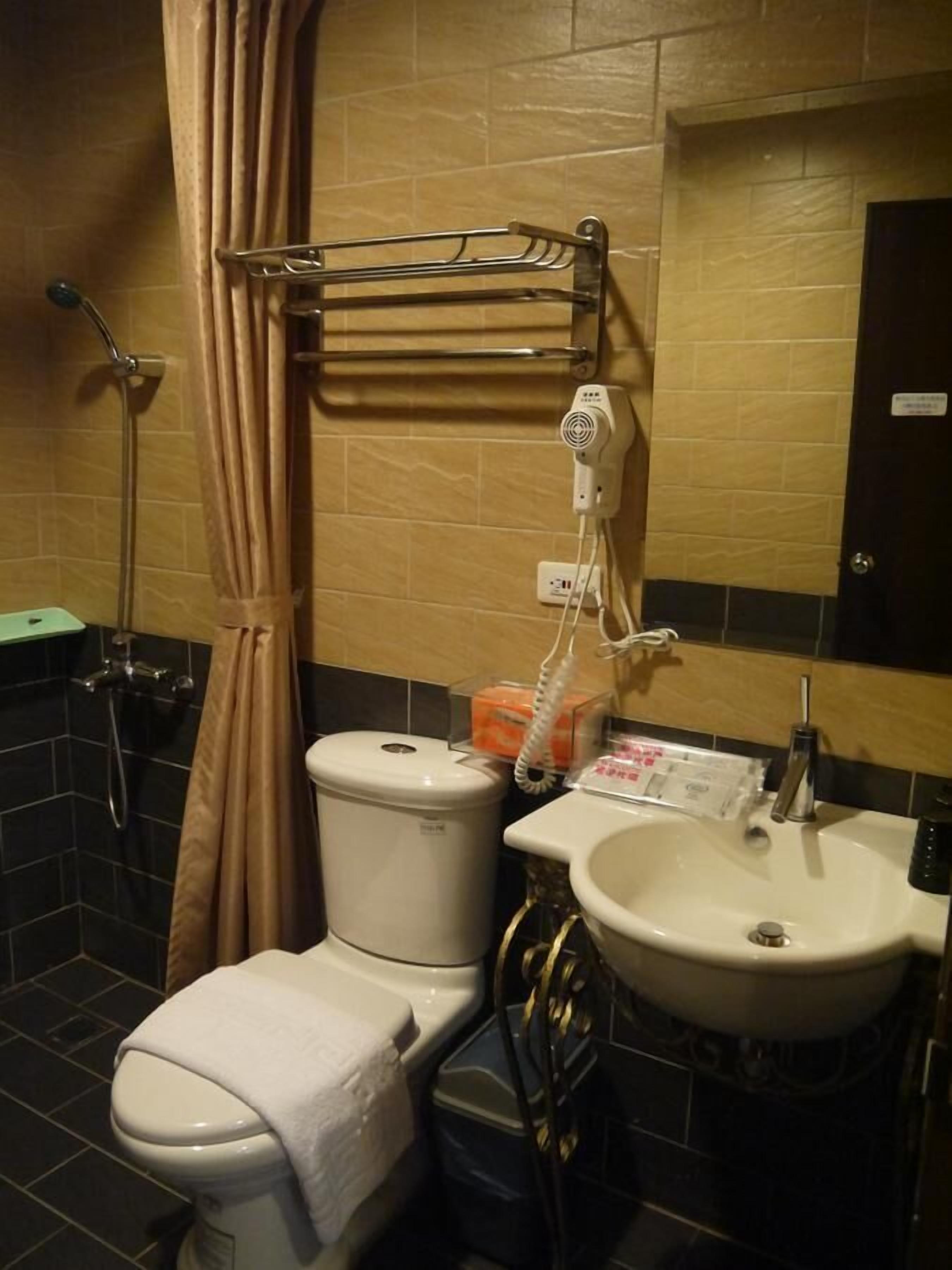 A bathroom with a toilet, sink, and shower.