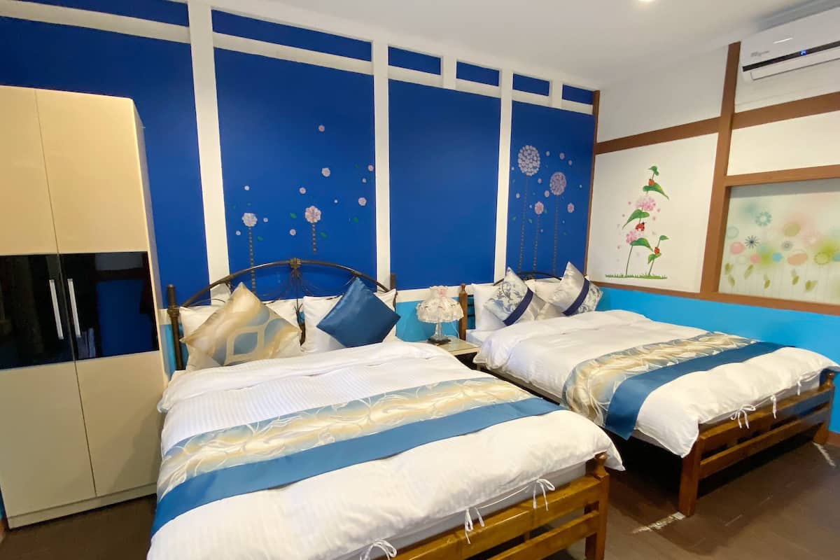 Habitación de hotel con dos camas individuales, un armario y una pared decorada con motivos florales.