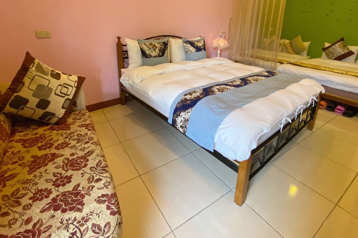 Un dormitorio con cama, sofá y ventana con cortinas.