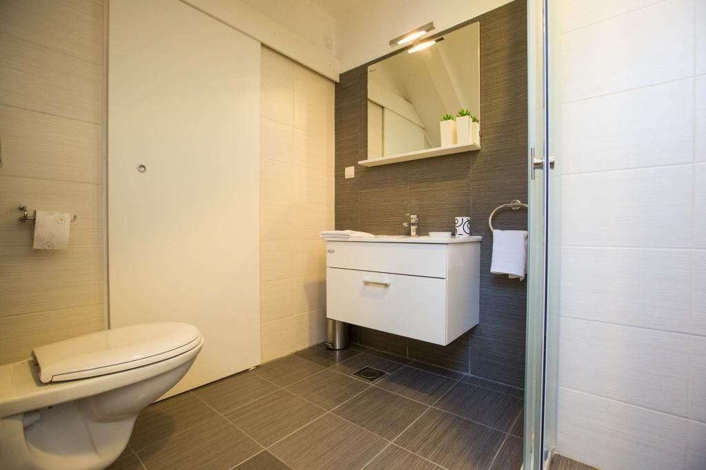 A modern bathroom with a toilet, a sink, and a mirror.