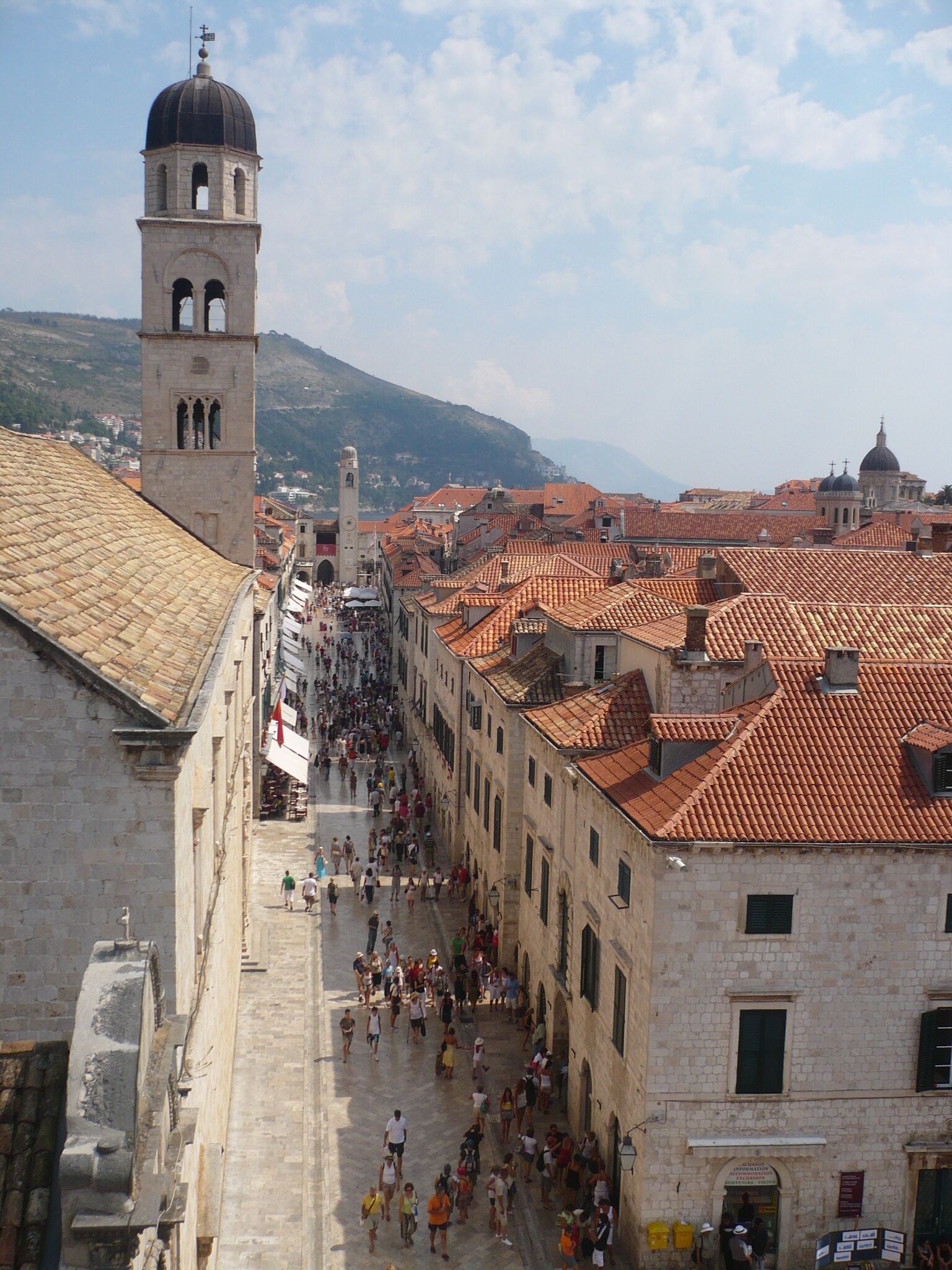 A historic street with a prominent tower and red-tiled buildings.