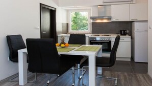 A compact kitchen with white cabinets, a stove, and a window. - Villa Mia (Dubrovnik)