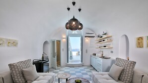 Een moderne woonkamer met een zwart-wit betegelde vloer, twee banken met opvallende kussens, een ronde salontafel en een decoratieve lamp.