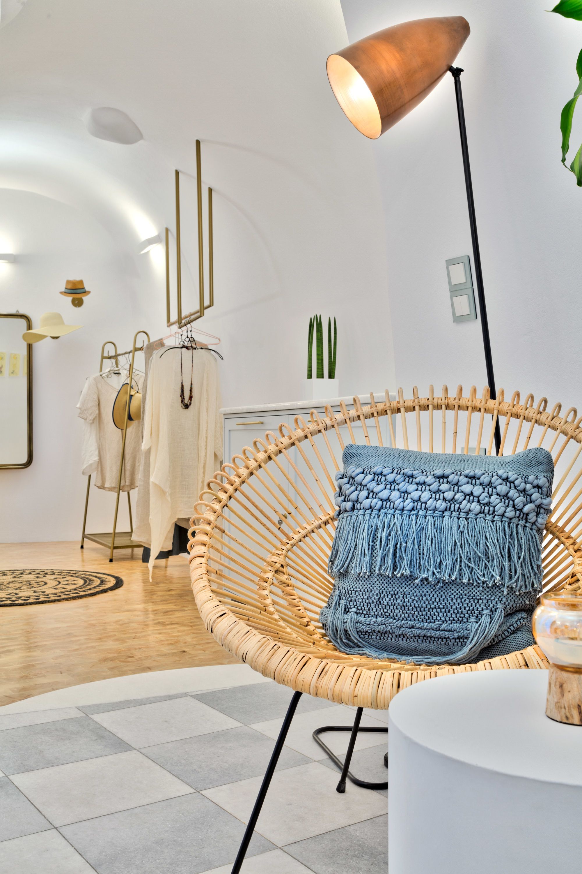 Un intérieur moderne avec un fauteuil en osier, une table ronde et un portant à vêtements.
