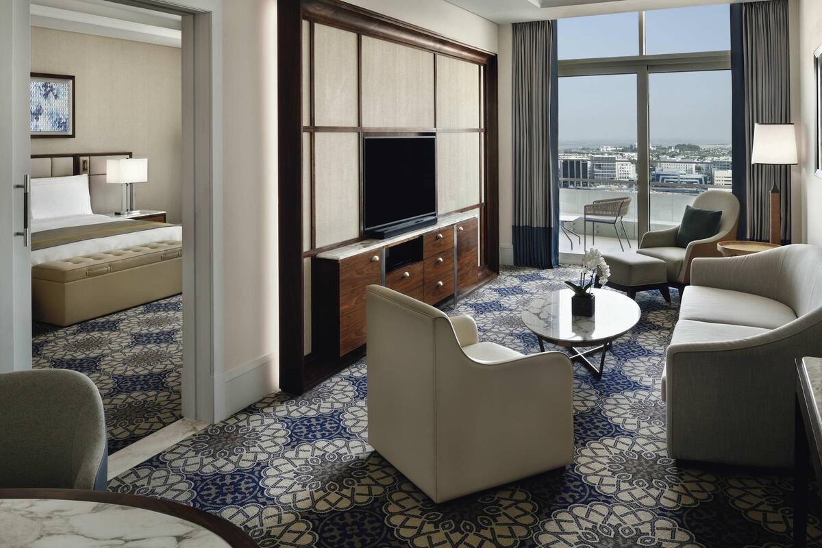 Habitación de hotel con cama, televisión, sofá, mesa de centro y vista panorámica de la ciudad.