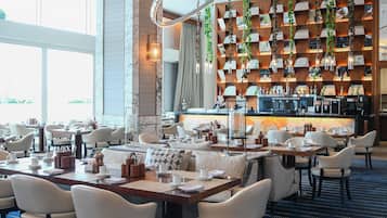 Un restaurant moderne doté d’un bar, de murs en marbre et offrant différents types de sièges.