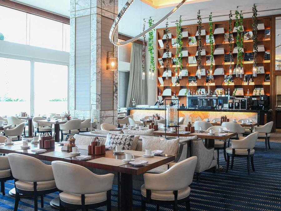 Un restaurant moderne doté d’un bar, de murs en marbre et offrant différents types de sièges.