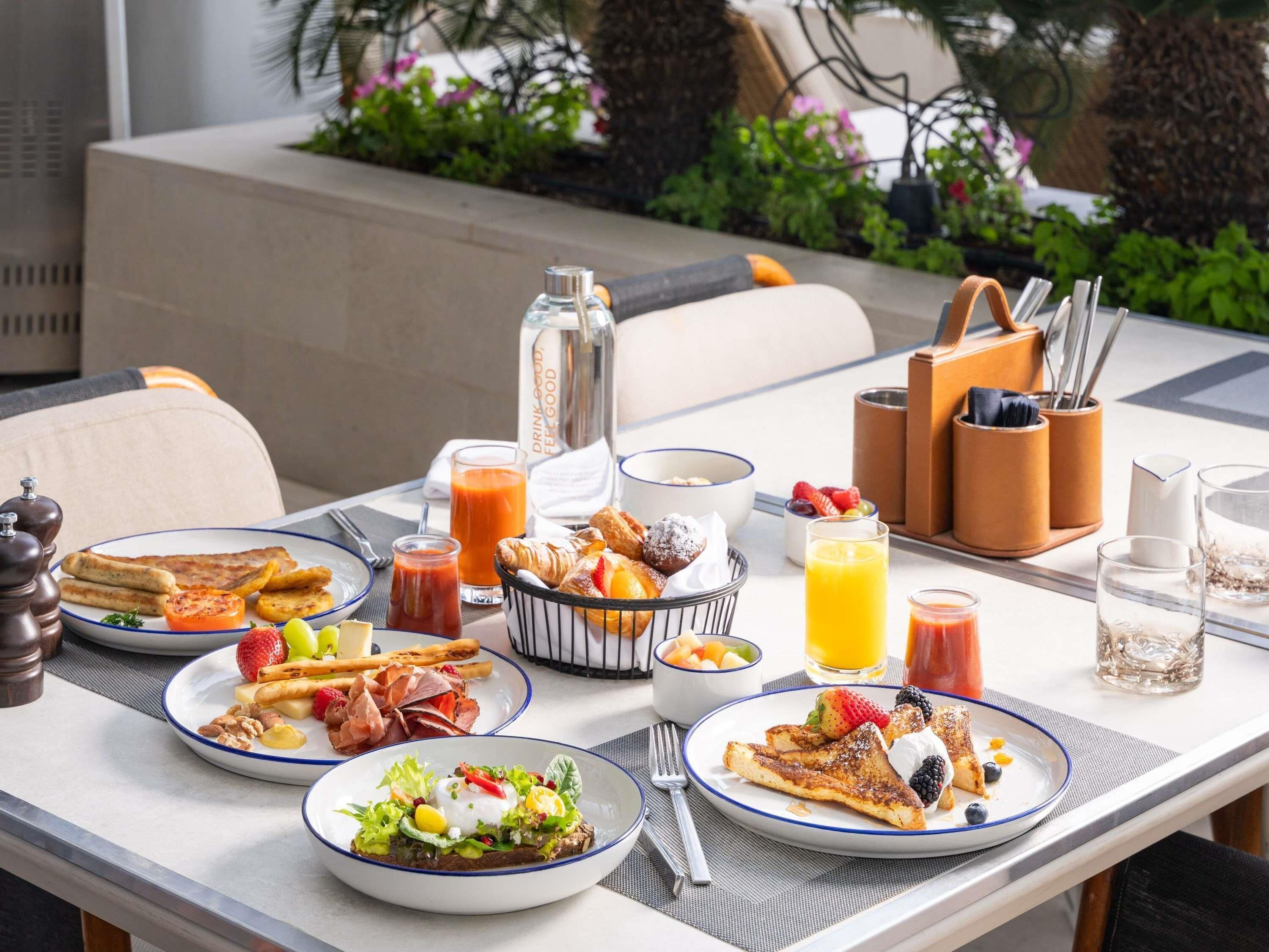 Una escena de desayuno con platos de comida, un vaso de jugo de naranja y una botella de jugo.
