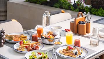 Una escena de desayuno con platos de comida, un vaso de jugo de naranja y una botella de jugo.