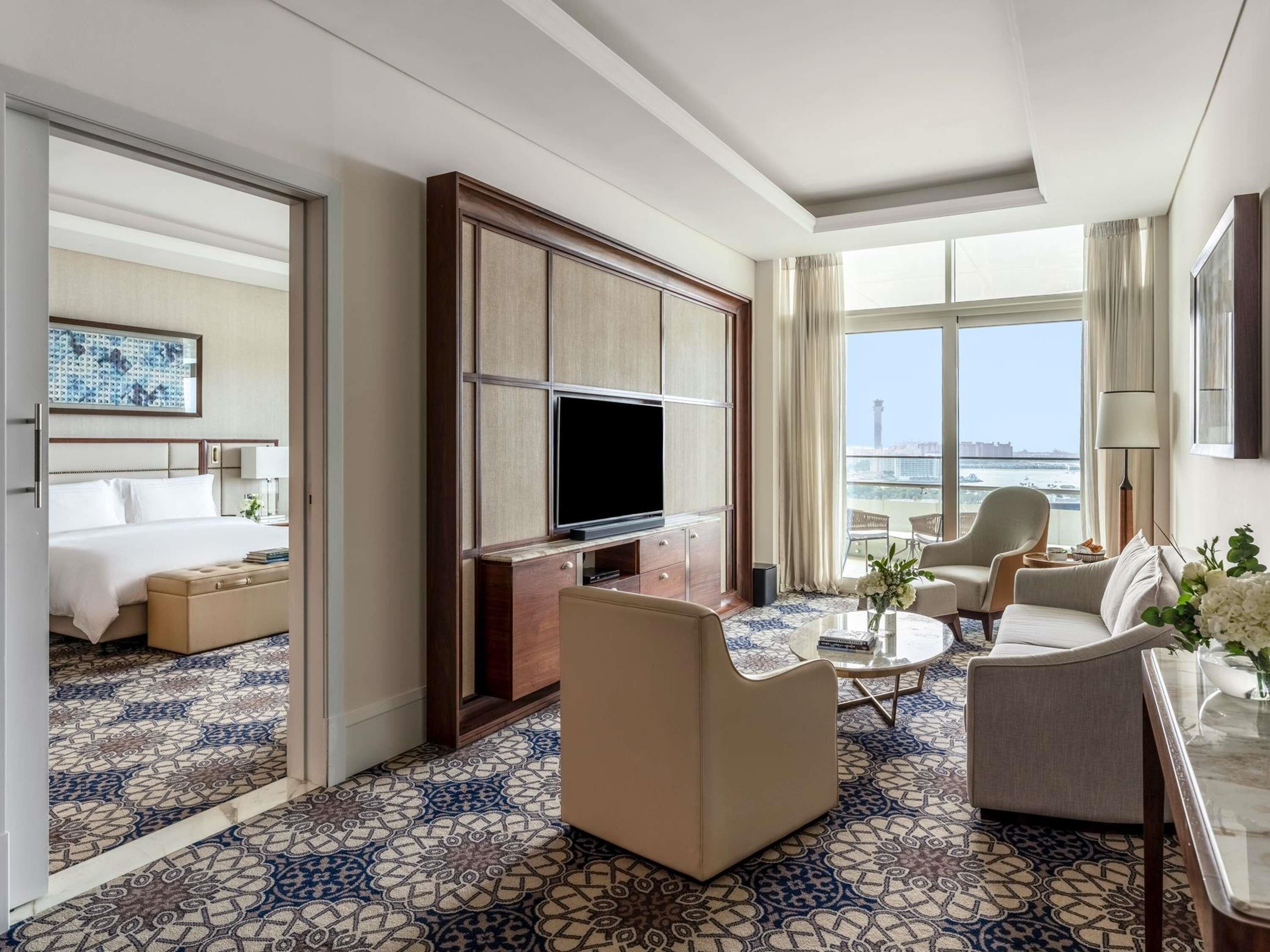 Une chambre d’hôtel équipée d’un lit, d’une télévision, d’un canapé, d’une table basse et offrant une vue sur la ville.