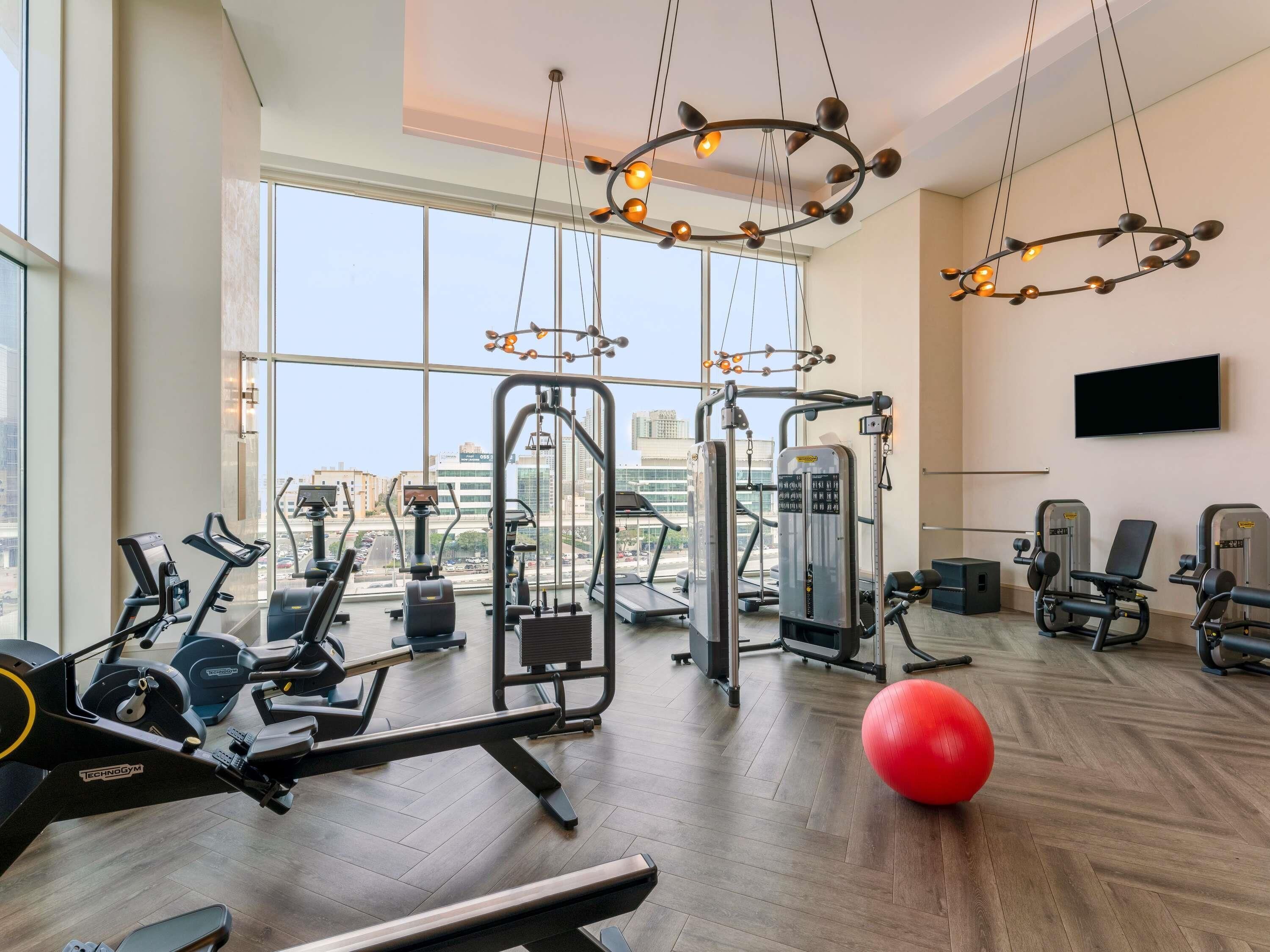 Ein Fitnessraum mit Cardiogeräten, Kurzhanteln und einem roten Trainingsball.
