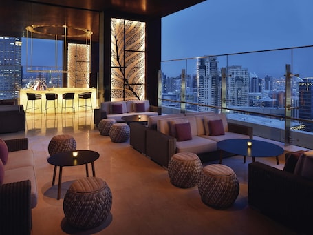 A modern lounge with a city view, featuring a bar area, sofas, and round tables.. Grand Plaza Mövenpick Media City