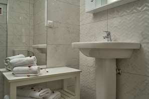 A bathroom with a white sink, a mirror, and a towel rack with folded towels. - Playa Del Zante (Zakynthos)