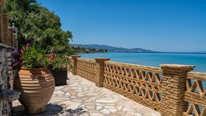 A stone-paved terrace with a decorative fence, potted plants, and a view of the sea. - Playa Del Zante (Zakynthos)