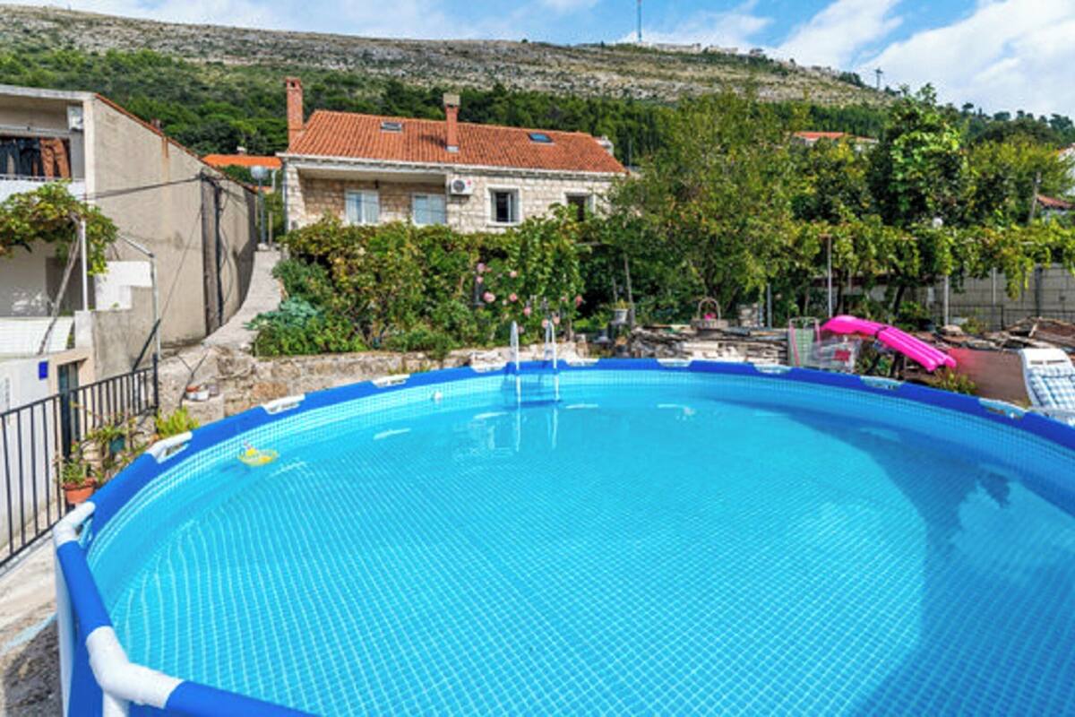 A swimming pool with a blue tiled deck, surrounded by lounge chairs and umbrellas, with a hillside in the background.