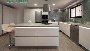 A modern kitchen with a central island, built-in appliances, and a backsplash. - Casa da Rosalina (Calheta)