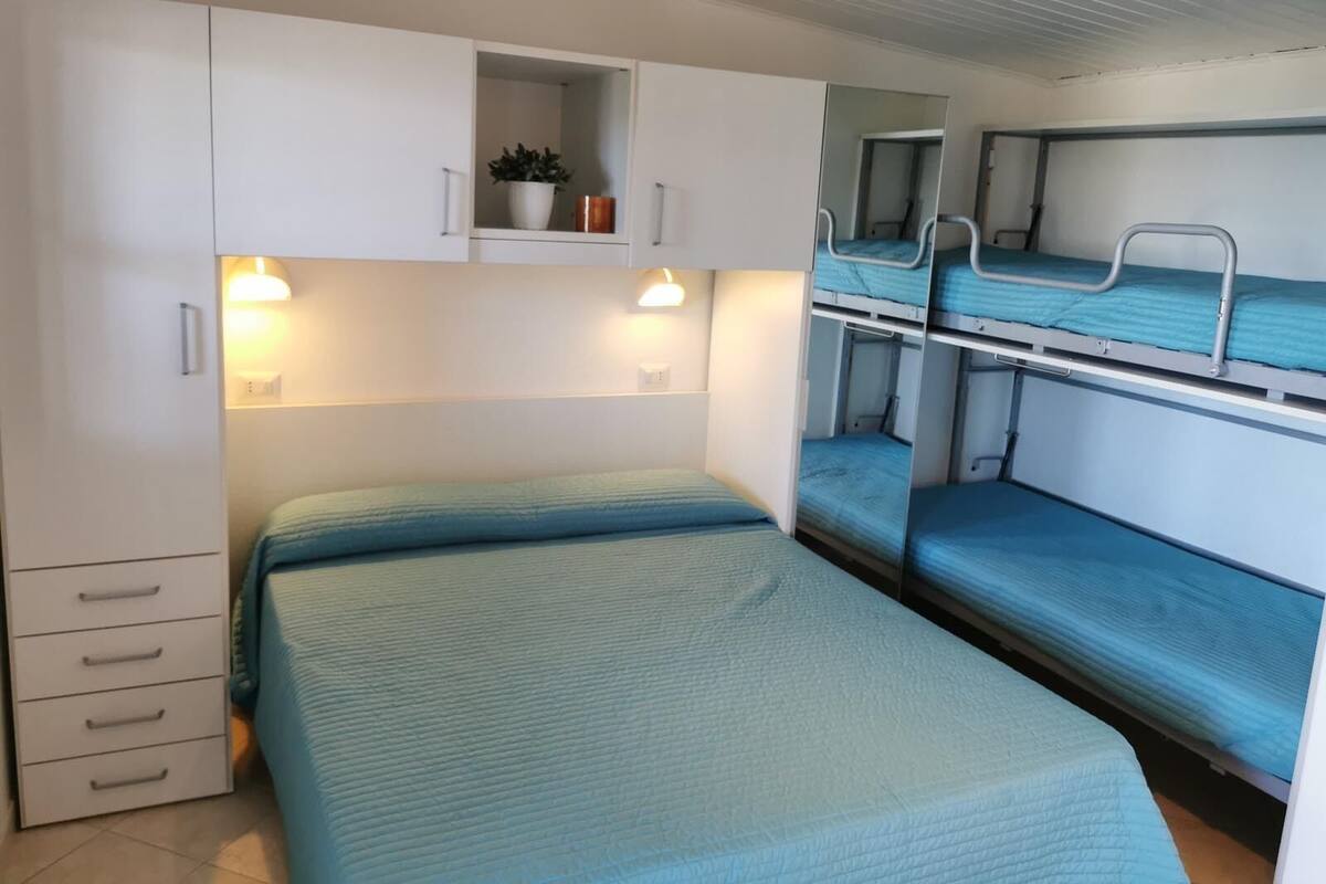 A bunk bed room with a single bed and a cabinet with drawers.