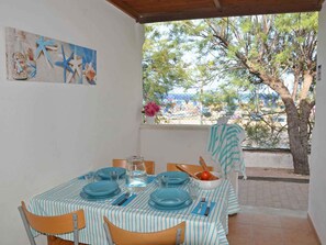 A dining area with a table set for four, featuring blue plates and glasses, a vase with flowers, and a painting on the wall. - Villaggio Gabbiano Beach (Vieste)