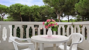 A round table with a vase of flowers, two white chairs, and a balcony railing. - Residence Rubin (Lignano Sabbiadoro)