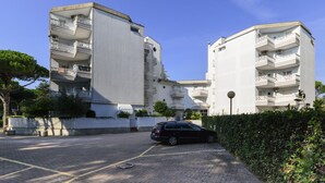 A modern apartment building with multiple balconies and a paved parking area. - Residence Rubin (Lignano Sabbiadoro)