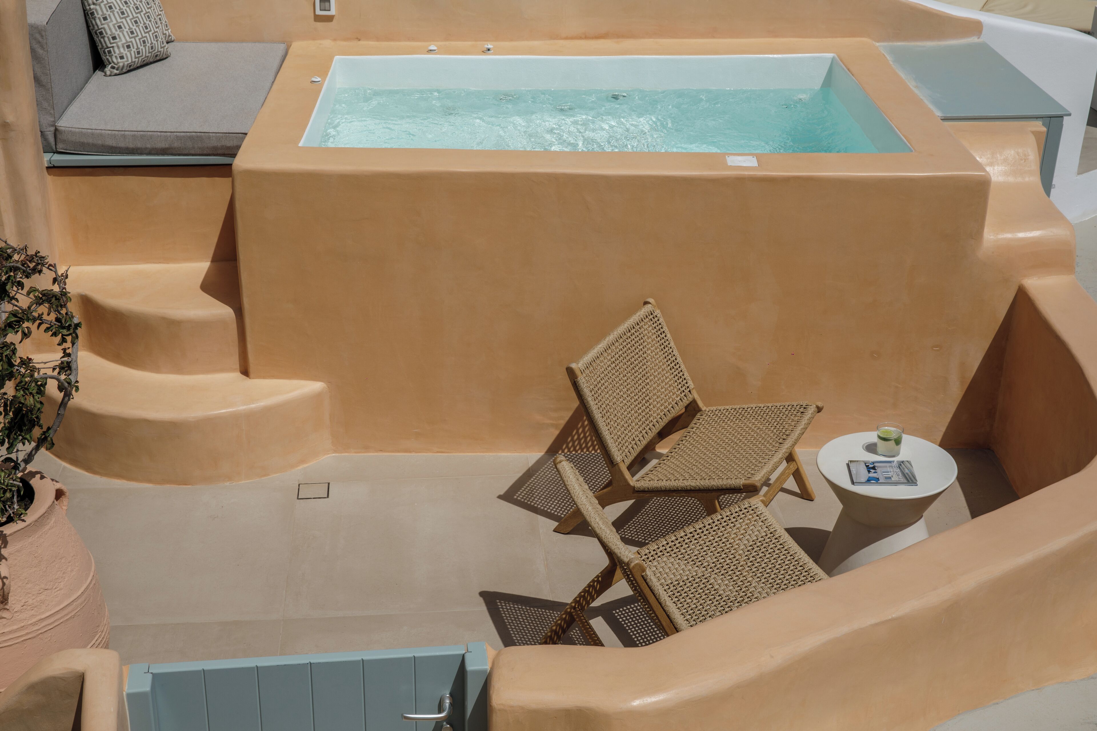 A spa area with a hot tub, lounge chairs, and a small table with a drink.