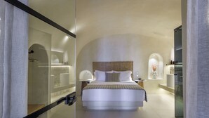 Ett modernt hotellrum med en stor säng, en glasvägg och en minimalistisk design.