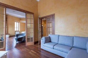 Relax in a spacious living area with a large sofa and vintage armchair, perfect for unwinding in style.