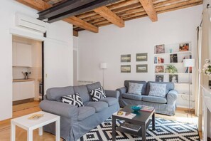 Una sala moderna con dos sofás grises, una mesa de centro blanca y una alfombra estampada.