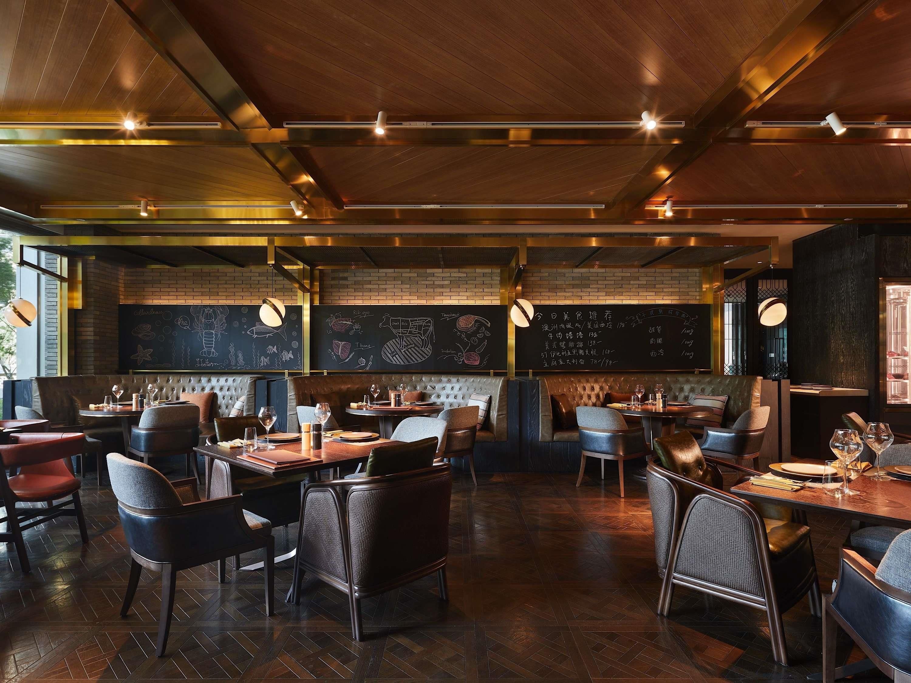 A restaurant interior with wooden floors, leather seating, and chalkboard menus.