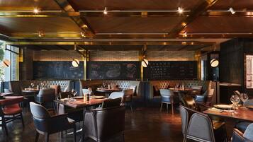 A restaurant interior with wooden floors, leather seating, and chalkboard menus.
