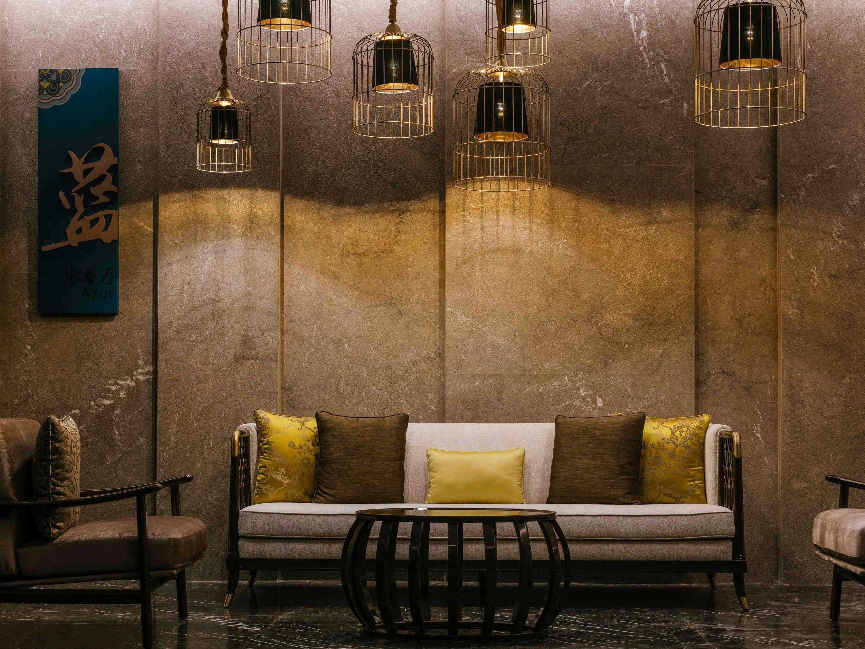 A modern interior with a sofa, chairs, and hanging light fixtures.