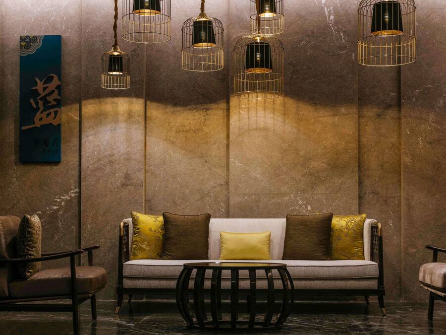 A modern interior with a sofa, chairs, and hanging light fixtures.