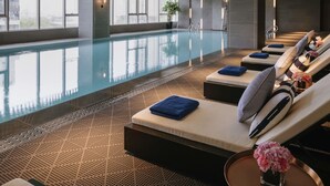 A modern indoor pool area with lounge chairs, a clear pool, and large windows. - Pullman Shanghai Qingpu Excellence (Shanghai)