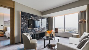 A modern hotel room with a large TV, comfortable seating, a marble accent wall, and a city view. - Pullman Shanghai Qingpu Excellence (Shanghai)