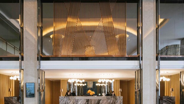 A modern hotel lobby with a marble reception desk, a large chandelier, and a high ceiling with a unique wooden slat design. - Pullman Shanghai Qingpu Excellence (Shanghai)